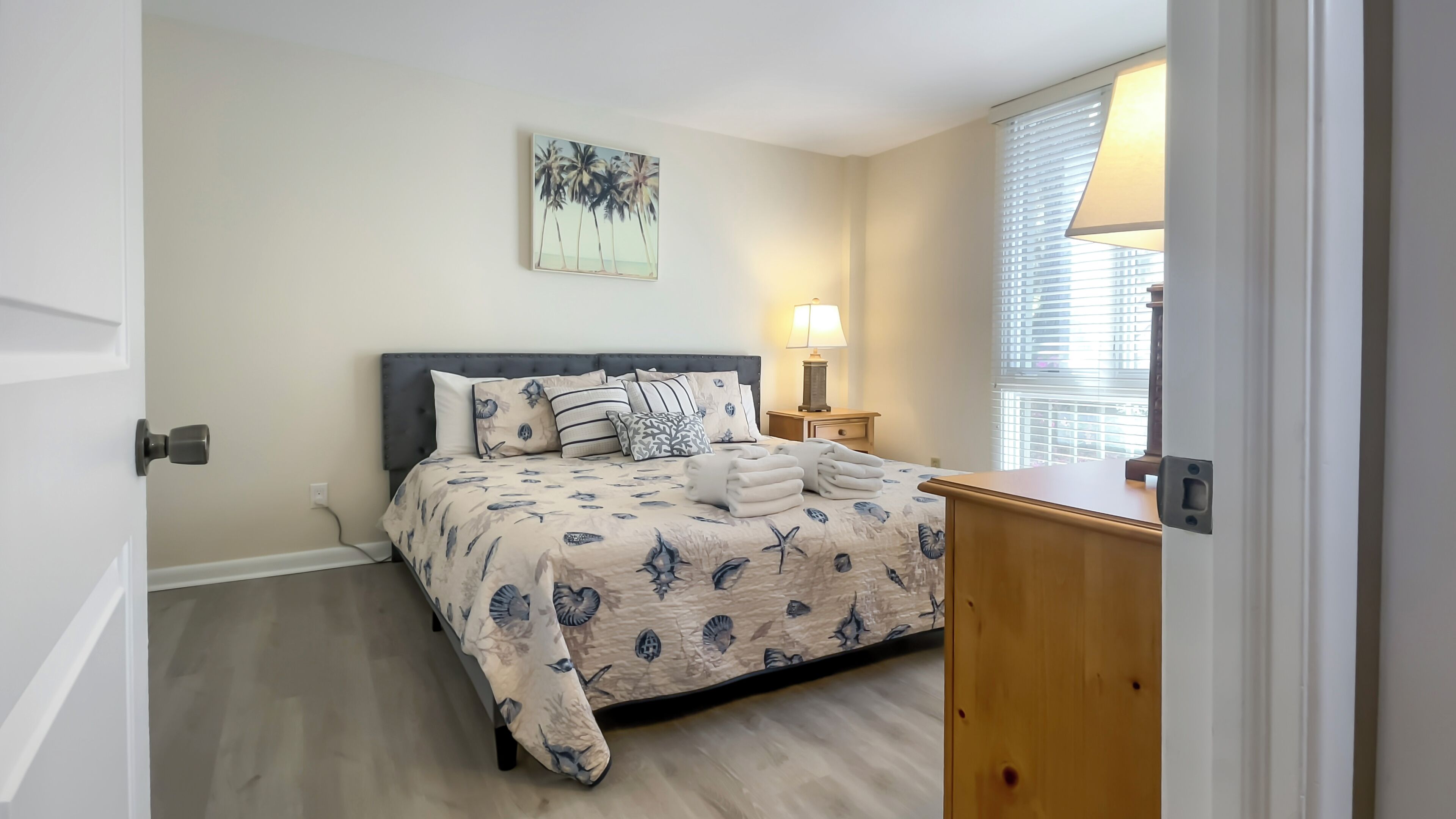 A bedroom with a bed, a nightstand, a lamp, and a window with blinds.