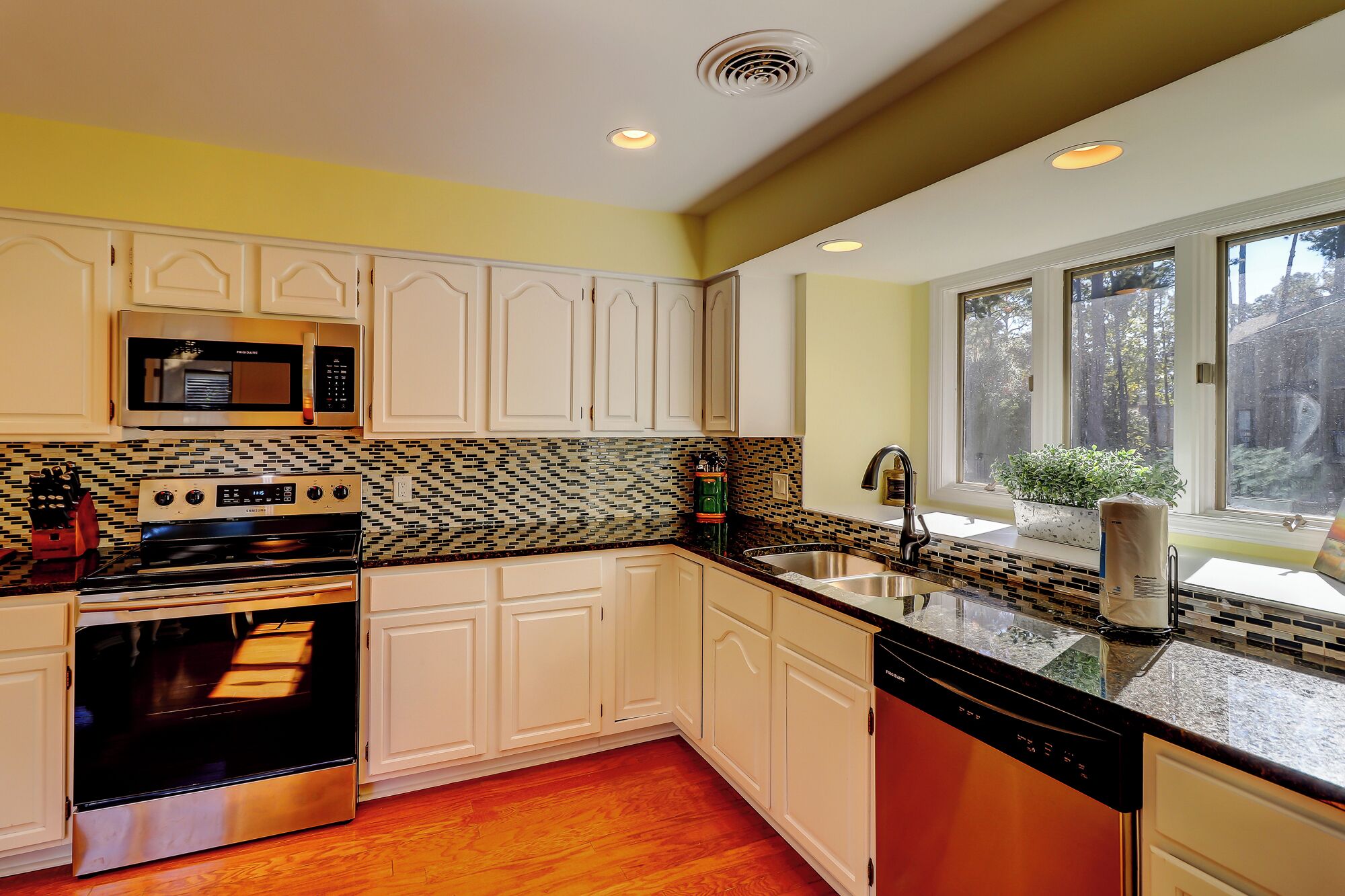 A kitchen with white cabinets, a stainless steel oven, a microwave, and a dishwasher.