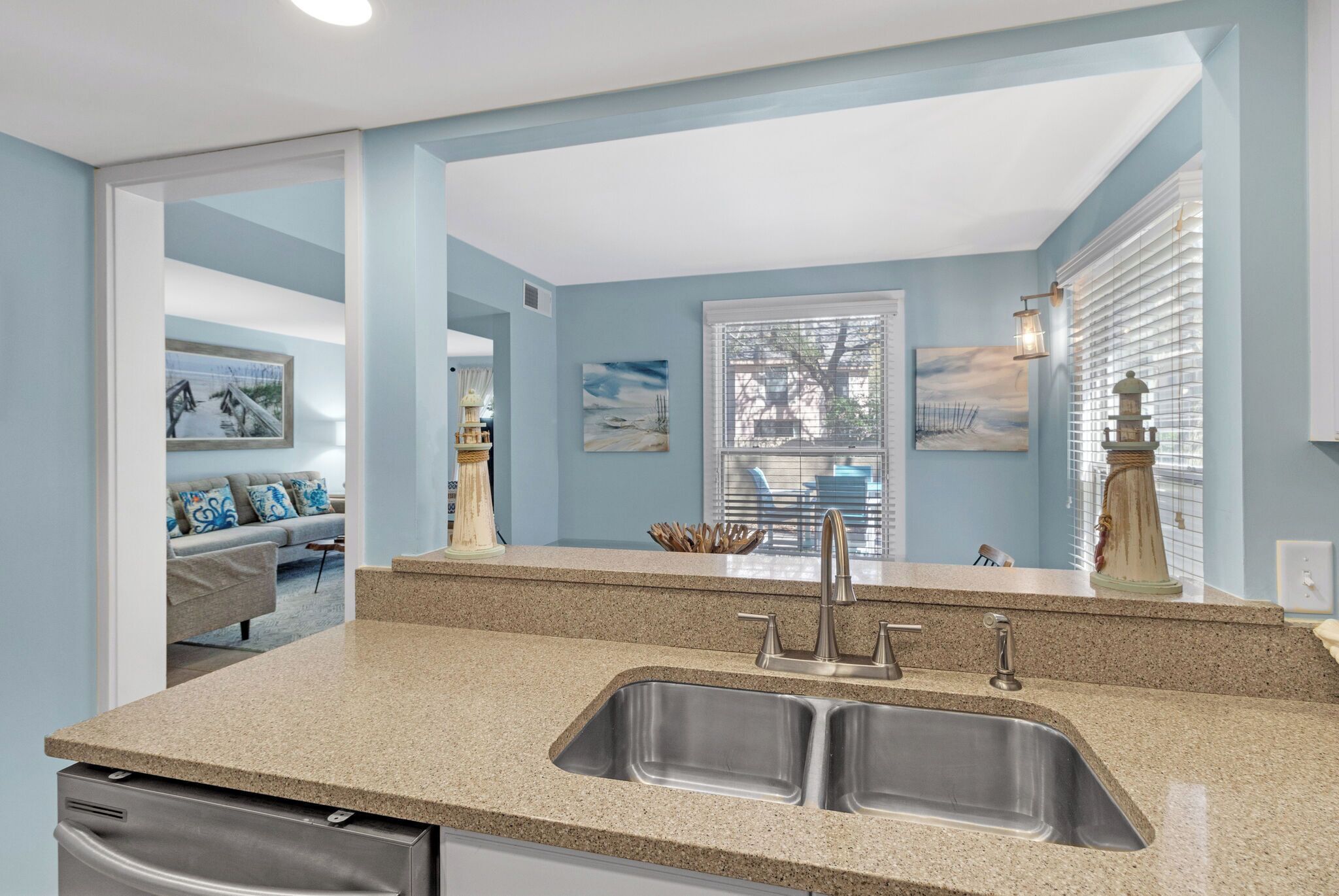 A modern kitchen with a double sink, granite countertop, and a view into the living area.
