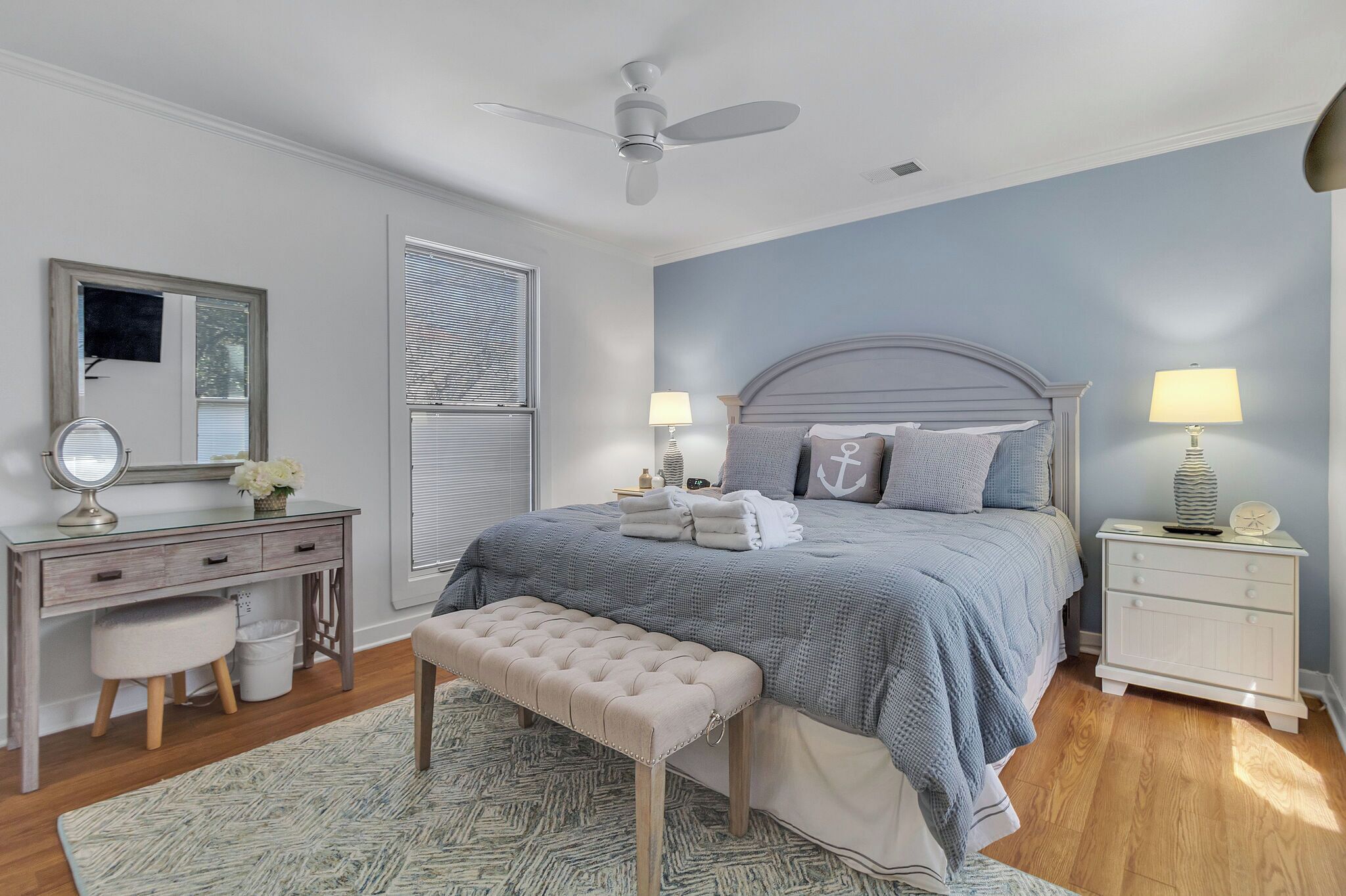 A bedroom with a bed, bedside tables, a desk, a chair, and a ceiling fan.