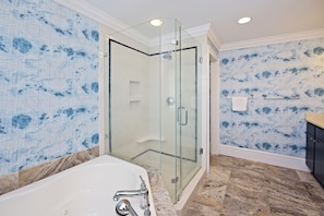 Une salle de bain moderne avec une douche à parois de verre, une baignoire blanche et des murs à motifs.