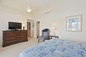 Une chambre à coucher comprenant un lit, une commode, une chaise et un téléviseur.