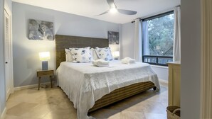 A neatly arranged bedroom with a bed, bedside lamps, and artwork on the walls. - 1045 Caravel Court at The Sea Pines Resort (Hilton Head Island)