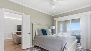 Un dormitorio con cama, mesita de noche, televisor, una silla y balcón con vistas.