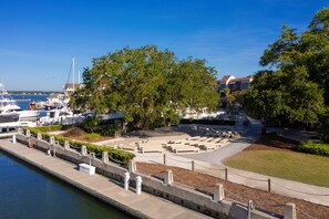 A marina with boats docked, a grassy area with benches, and a building in the background.