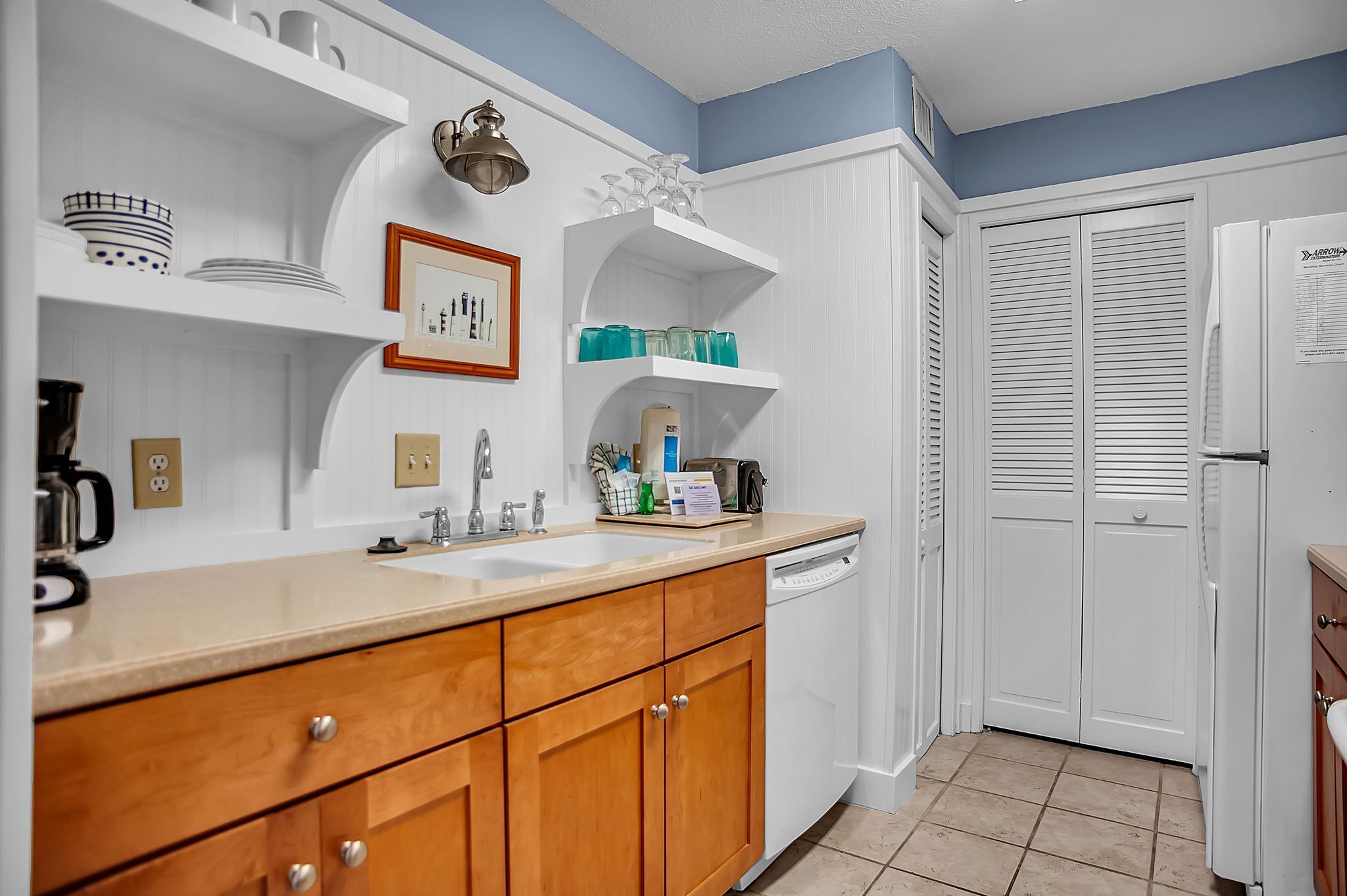 A kitchen with white cabinets, a double sink, and a refrigerator.