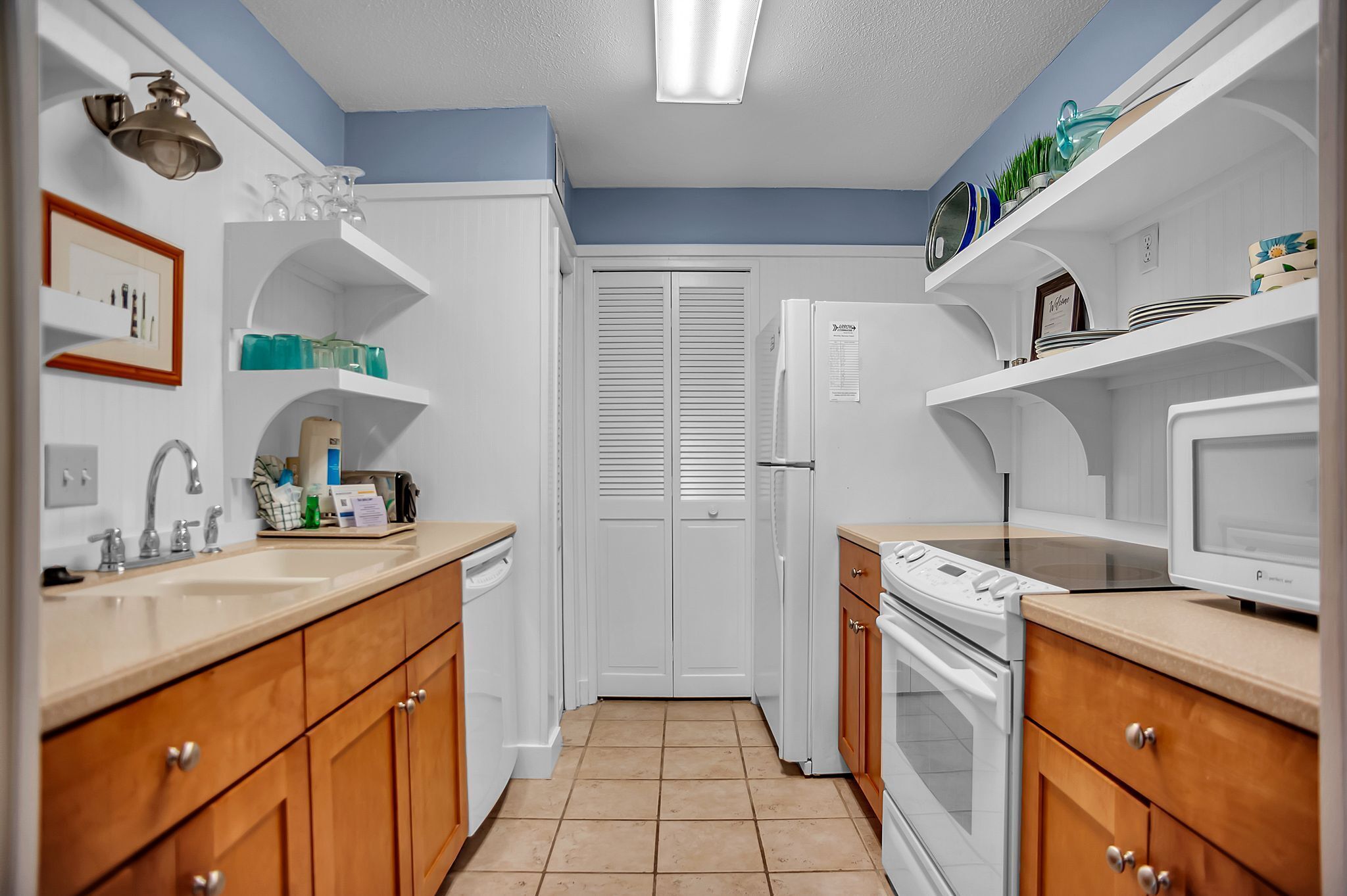 A kitchen with white cabinets, a stove, a microwave, and a refrigerator.