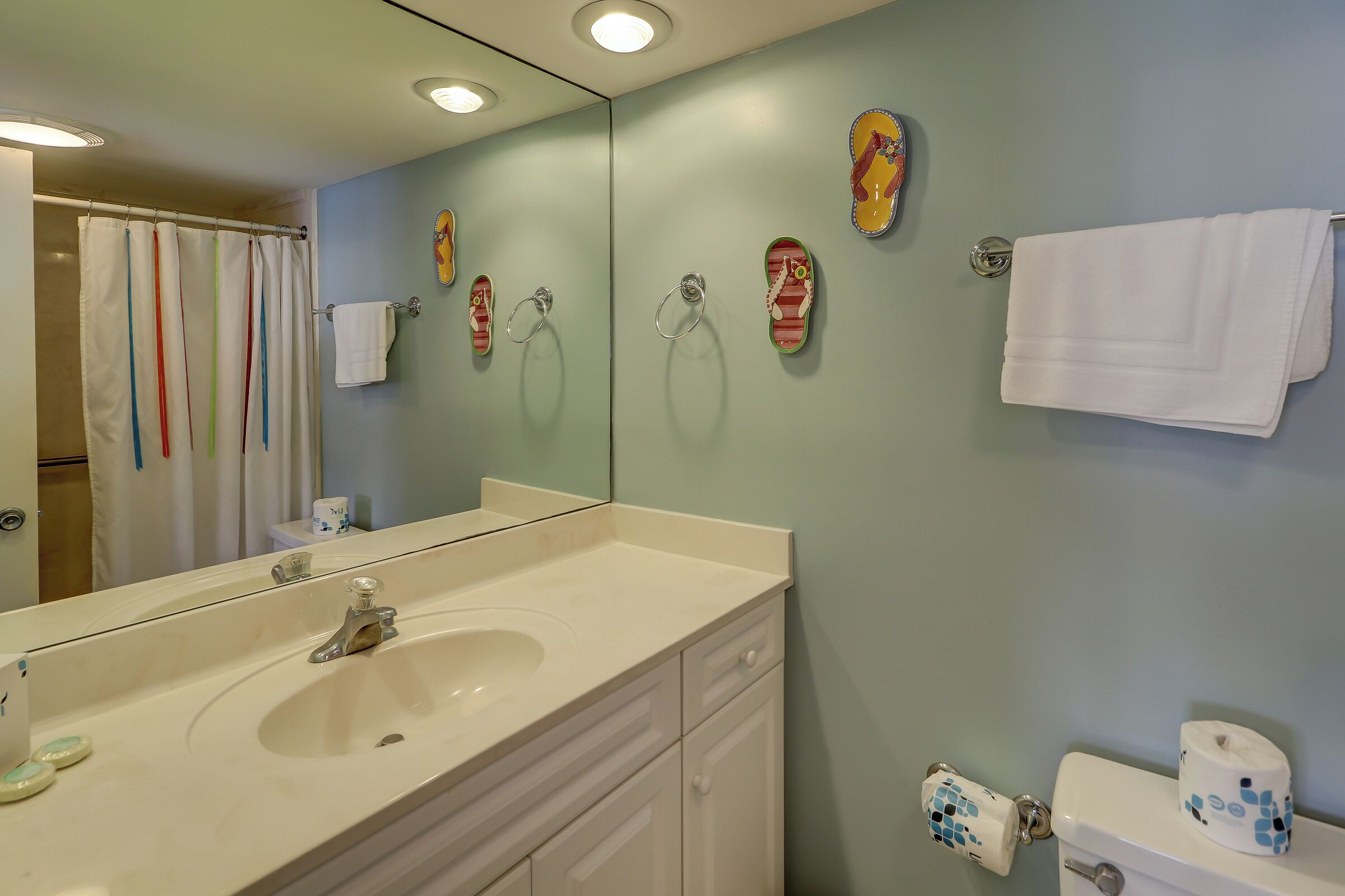 Une salle de bain équipée d’un lavabo, d’un miroir, d’un porte-serviettes et de toilettes.