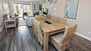 A dining area with a wooden table and wicker chairs, a chandelier, and a painting of a bird on the wall. - 904 Cutter Court at The Sea Pines Resort (Hilton Head Island)