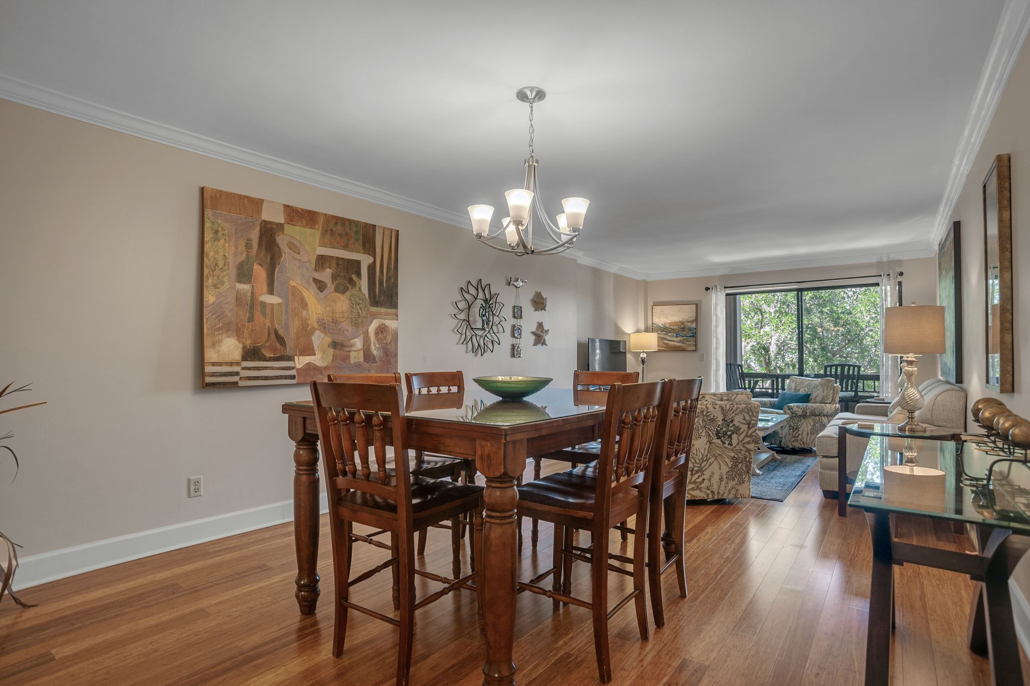 A dining area with a wooden table and chairs, a chandelier, and artwork on the walls.