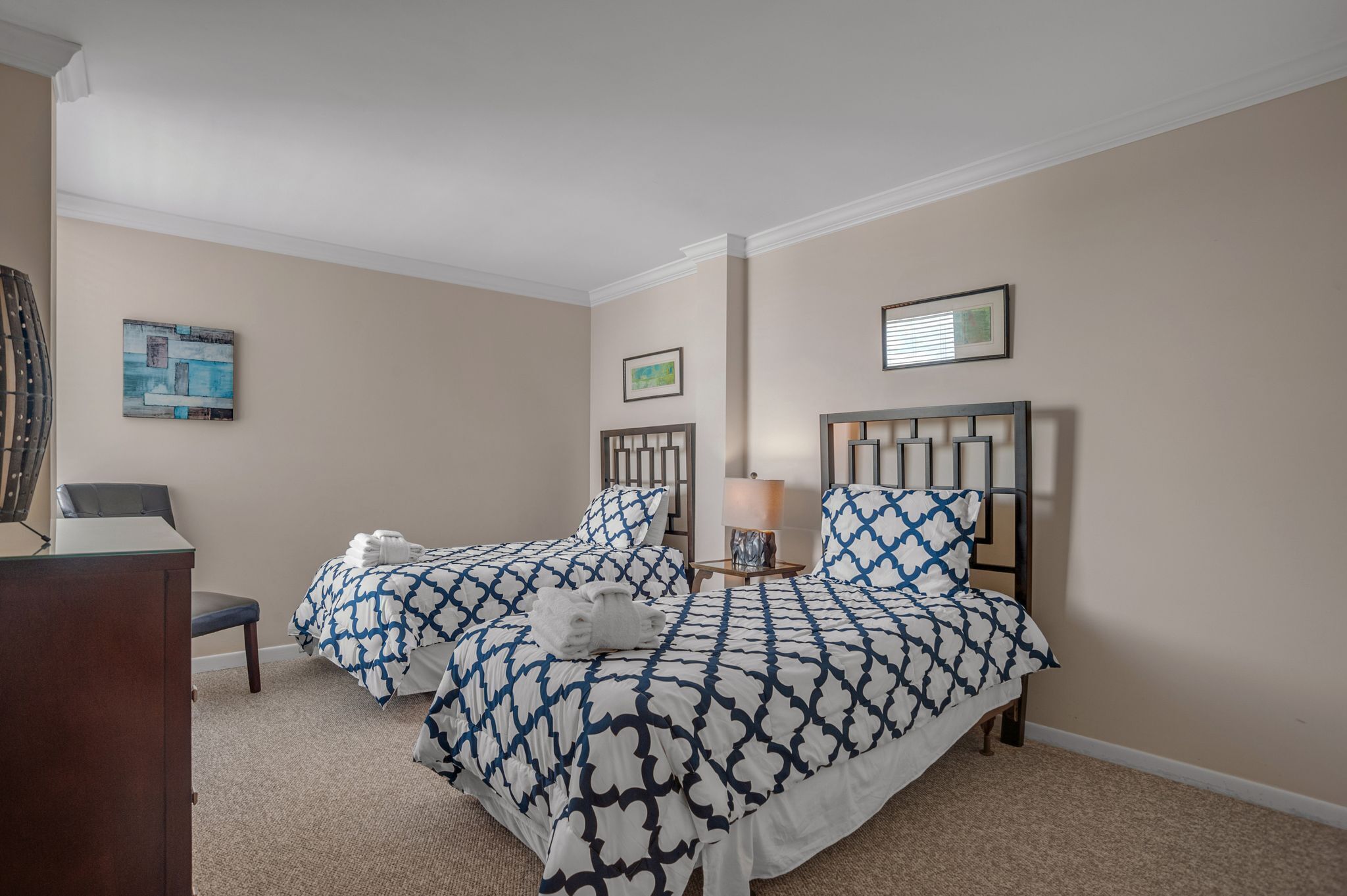 A hotel room with two beds, a desk, and a chair.
