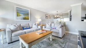 Ein modernes Wohnzimmer mit zwei Sofas, einem Holztisch und einem Bild mit Strandmotiv.