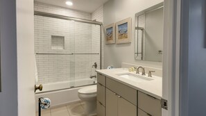 A modern bathroom with a white-tiled shower, a bathtub, a toilet, and a vanity with a sink and mirror. - 1034 Caravel Court at The Sea Pines Resort (Hilton Head Island)