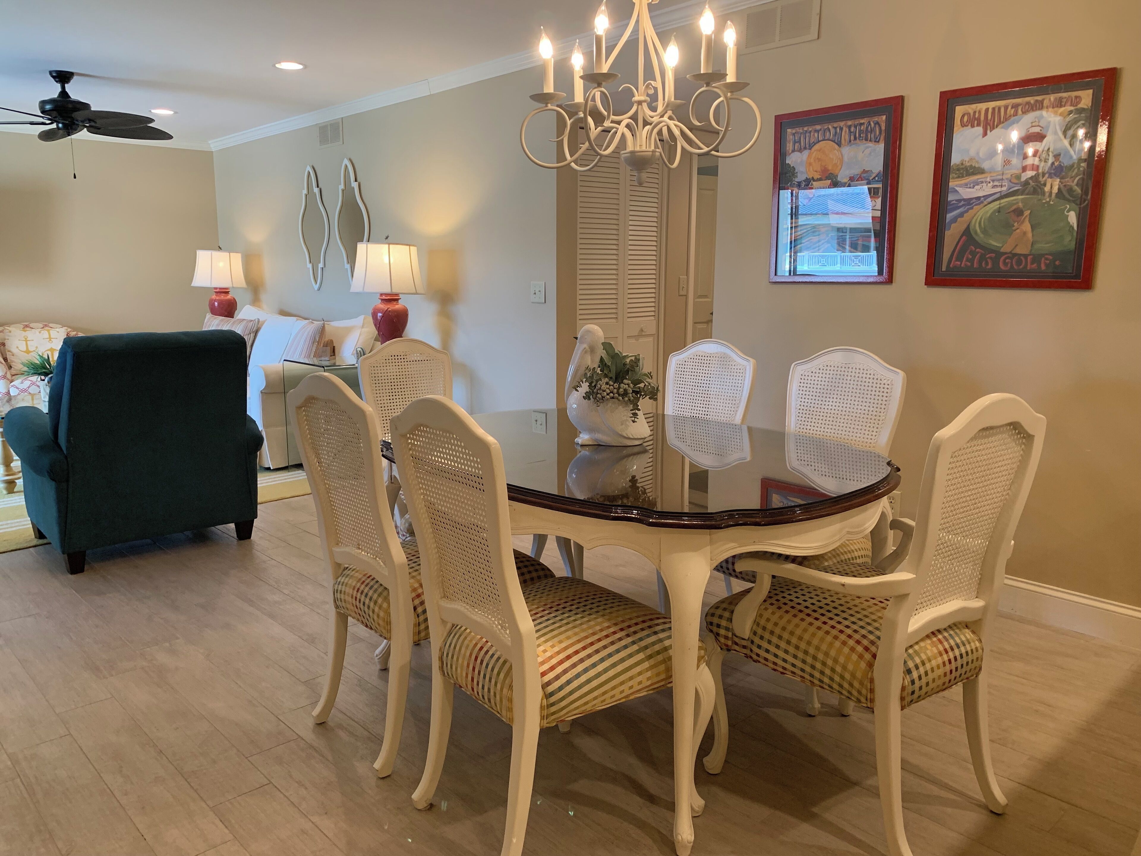 A dining area with a round table, white chairs, a chandelier, and two wall-mounted lamps.