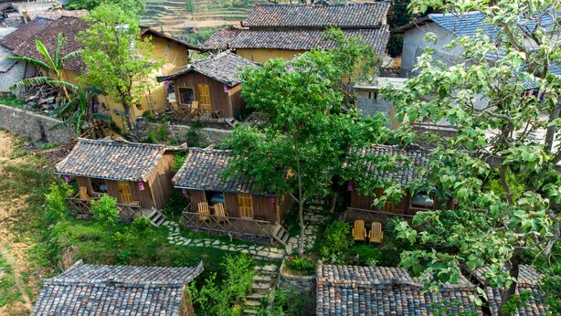 Un conjunto de casas tradicionales con techos de tejas, rodeadas de vegetación y un camino de piedra.