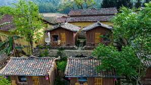 Un grupo de casas de madera tradicionales con tejados de tejas, rodeadas de exuberante vegetación y senderos de piedra.