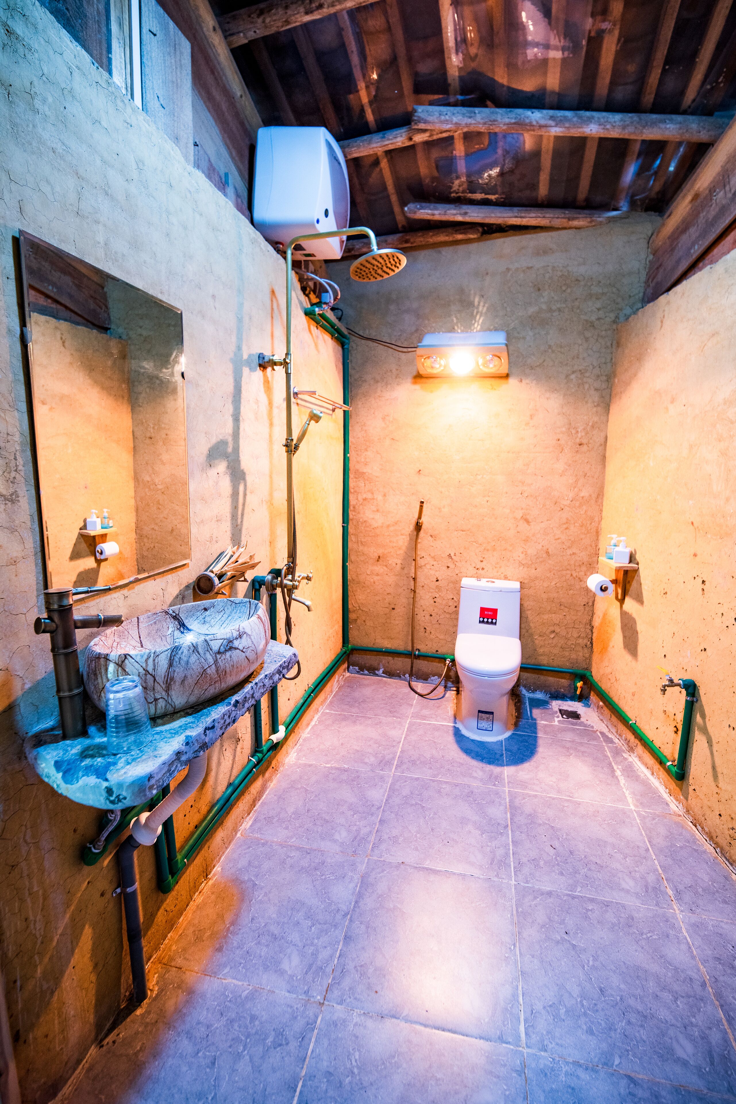 Een kleine, rustieke badkamer met een marmeren wastafel, toilet en douche.