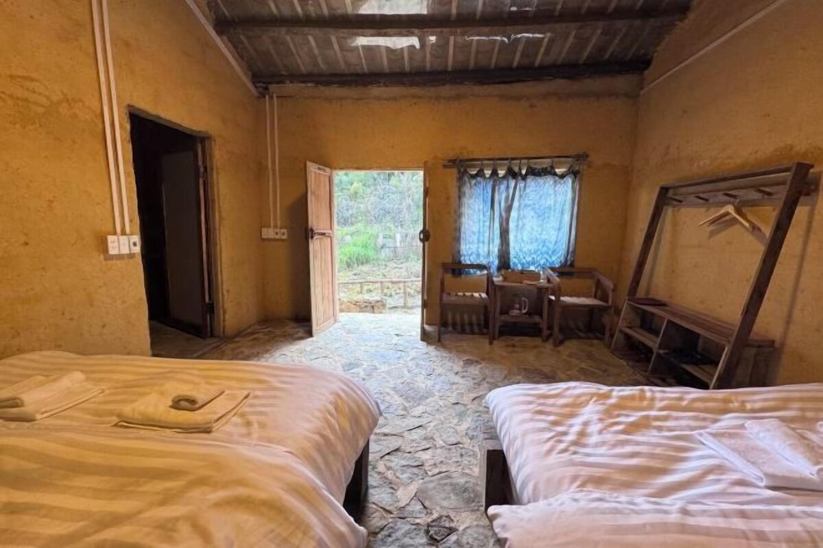 A room with two beds, a desk, and a window with curtains.