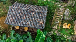 Una casa tradicional con tejado de baldosas, rodeada de abundante vegetación y un sendero de piedra.