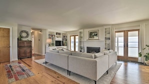 A spacious living room with a large sectional sofa, wooden flooring, and a fireplace.