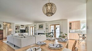 A spacious living room with a sofa, dining table set with placemats and plates, and a hanging light fixture.