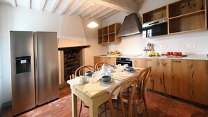 Une cuisine avec une table en bois dressée pour le repas, un réfrigérateur et une cuisinière.