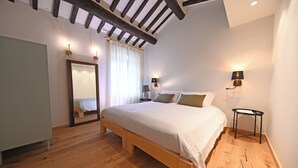 Une chambre à coucher avec un lit en bois, une table de chevet, un miroir et deux lampes fixées au mur.