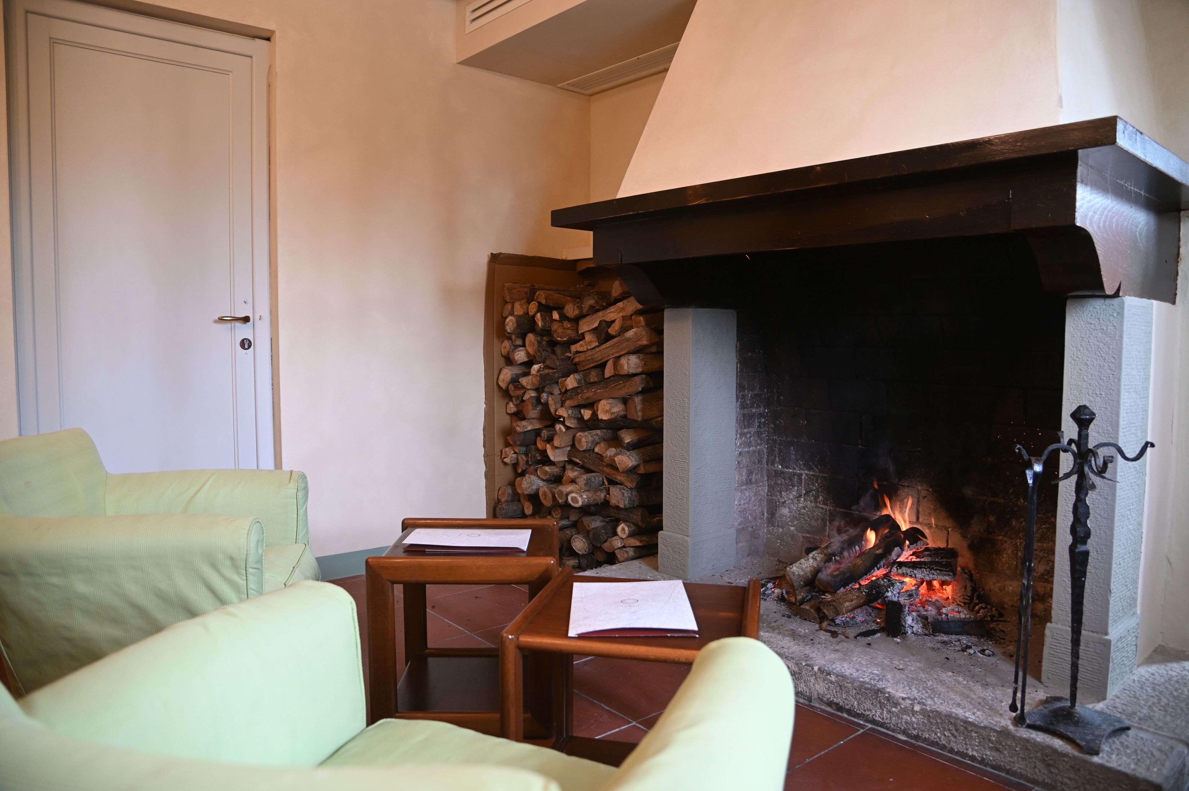 Une pièce chaleureuse avec une cheminée, une porte et deux fauteuils.