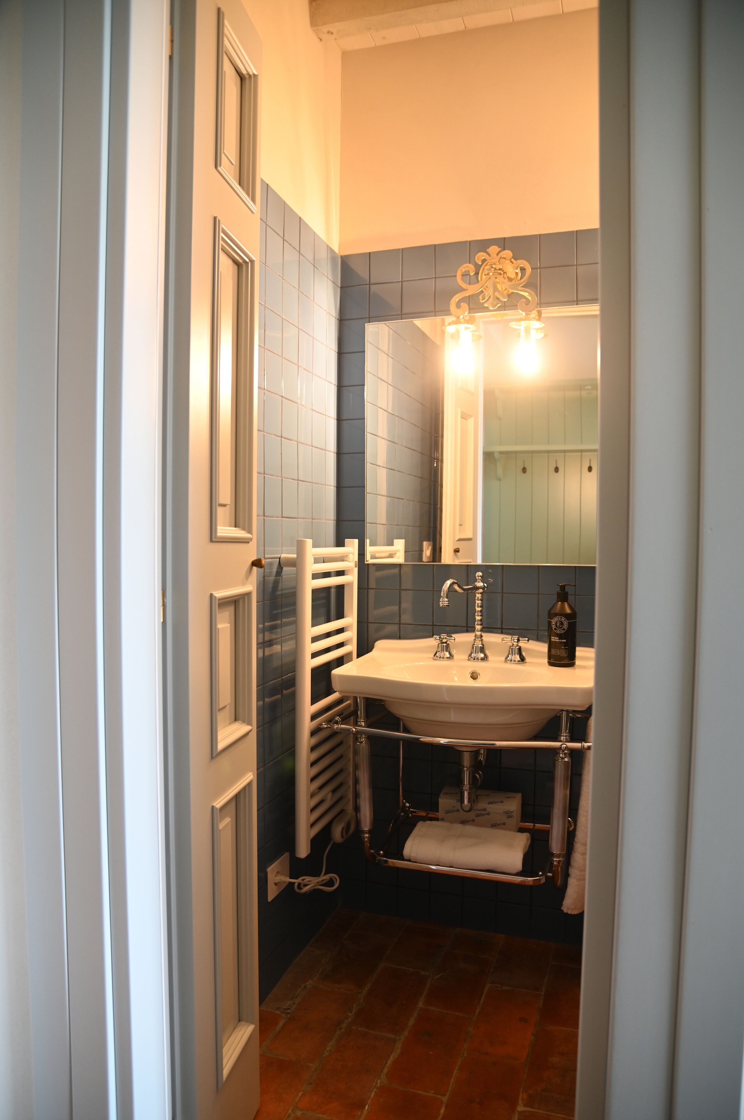 Une salle de bain avec un lavabo blanc, un miroir et un porte-serviettes.