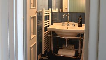 Une salle de bain avec un lavabo blanc, un miroir et un porte-serviettes.