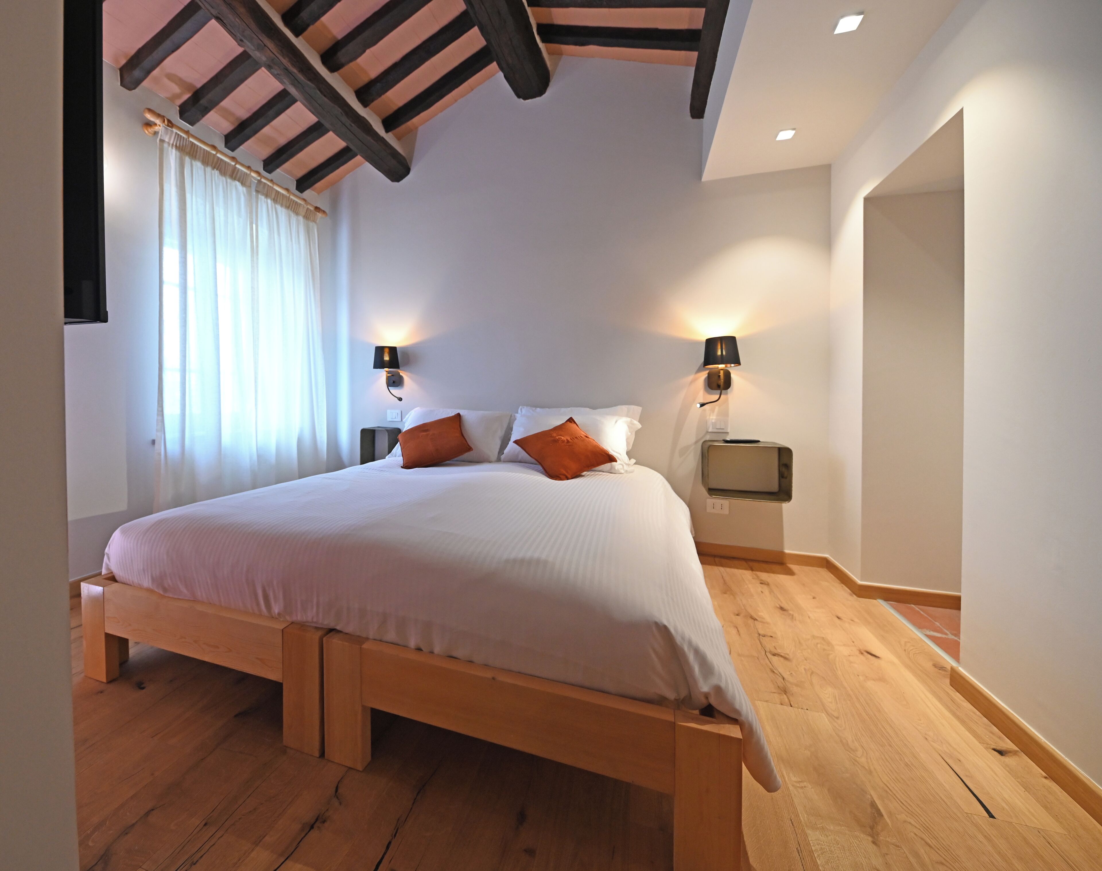 Un dormitorio con una cama de madera, dos lámparas de noche y un televisor pequeño.