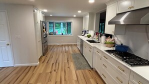 Een moderne keuken met houten vloer, witte kasten en een roestvrijstalen afzuigkap.