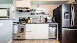 Una cocina compacta con un refrigerador de acero inoxidable, un microondas, un lavavajillas y un horno doble.