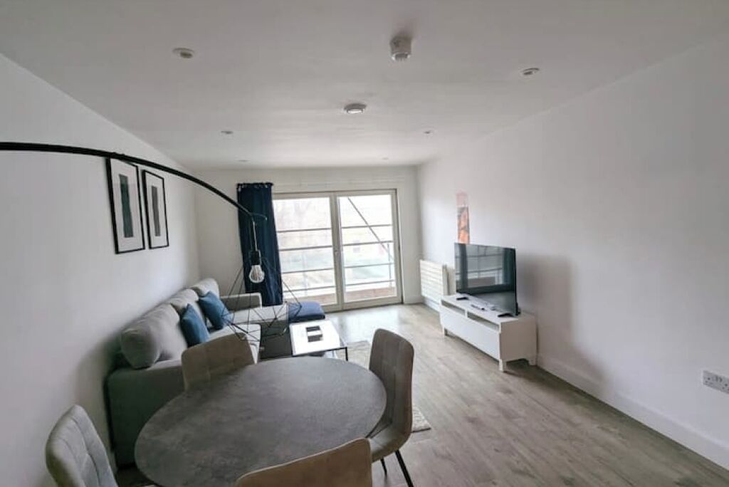 A modern living room with a dining table, sofa, and TV stand.