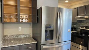 A kitchen with a stainless steel refrigerator, a built-in oven, and a granite countertop.