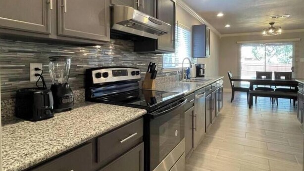 A modern kitchen with granite countertops, stainless steel appliances, and a dining area with a table and chairs.