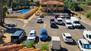 A hotel with a swimming pool, a parking lot with various vehicles, and a mountainous backdrop. - Magnificent T4 sea view (Carthagène)