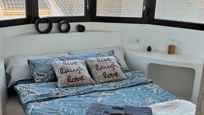 A bedroom with a bed, pillows, a window, and a view of a tiled roof and palm trees. - Magnificent T4 sea view (Carthagène)