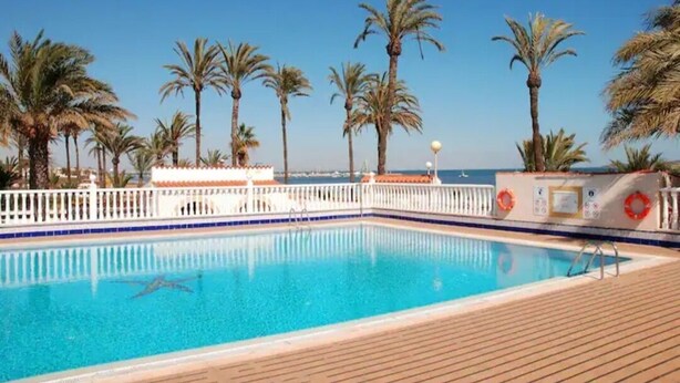 A swimming pool with clear blue water, surrounded by palm trees and a white fence. - Magnificent T4 sea view (Carthagène)
