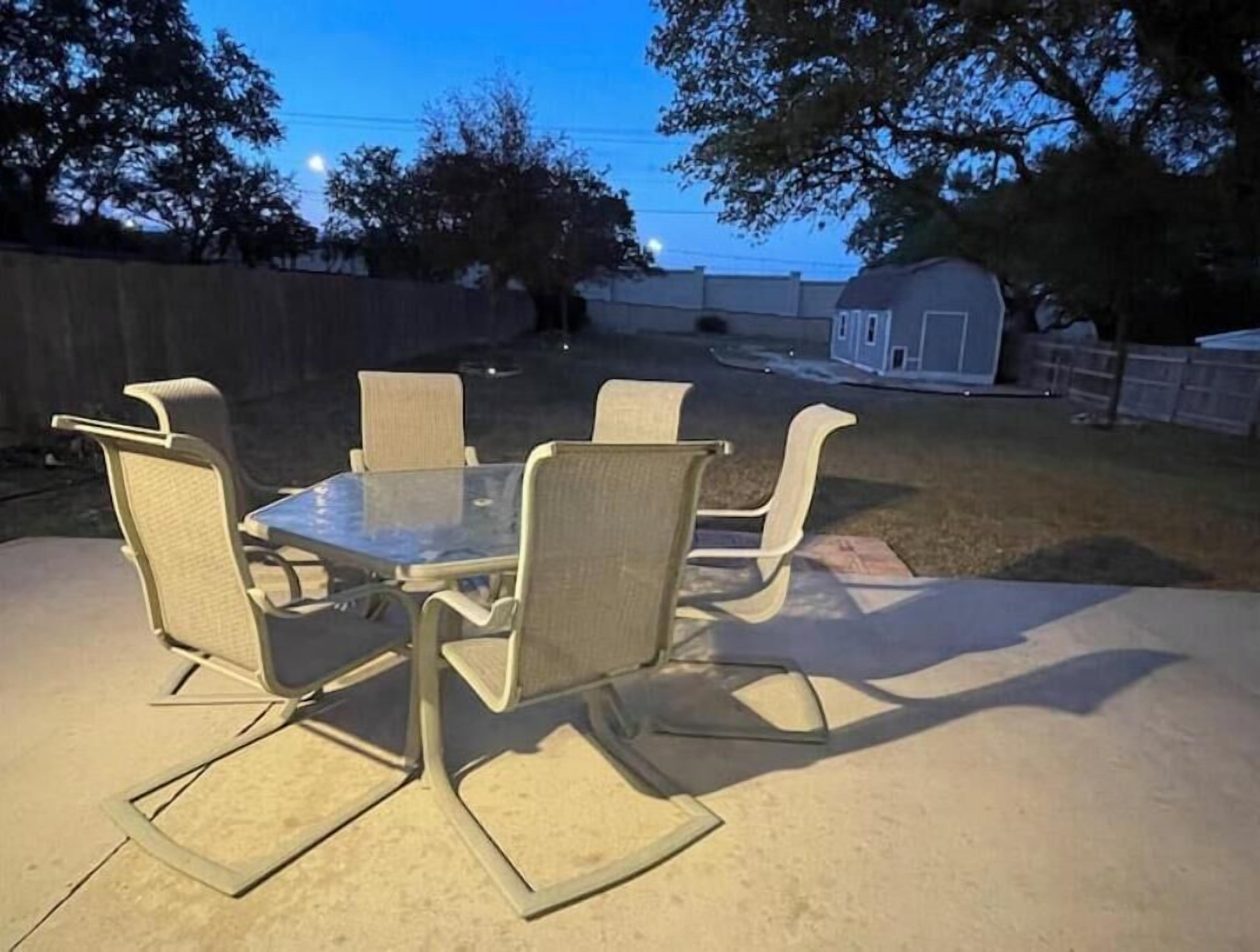 Une terrasse extérieure avec une table à plateau en verre et quatre chaises.