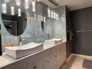 A bathroom with two sinks, a large mirror, and pendant lights.