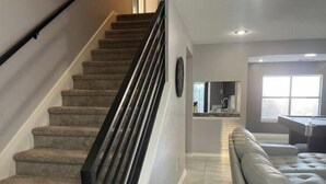 A staircase with carpeted steps and a black handrail, leading to a kitchen area with a countertop and a sink. - Spacious 5BR Longwood Home with Pool Table, Fenced Yard Near JW (San Antonio)