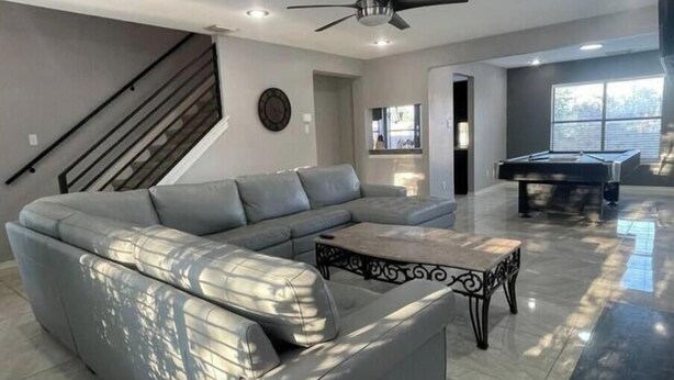 A modern living room with a sectional sofa, a pool table, and a ceiling fan. - Spacious 5BR Longwood Home with Pool Table, Fenced Yard Near JW (San Antonio)