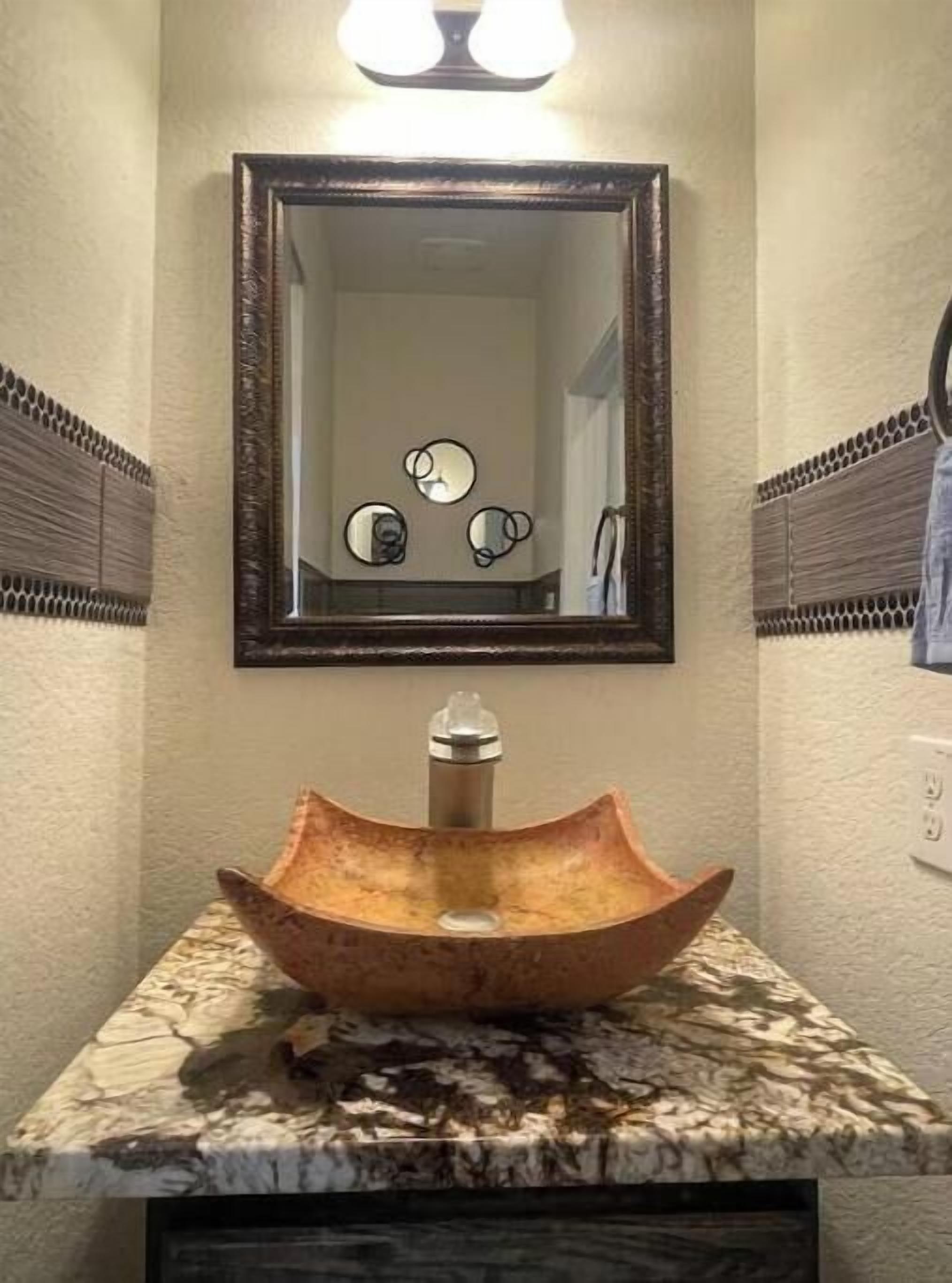 Un bagno con lavabo in marmo, uno specchio e un fiorile a parete.
