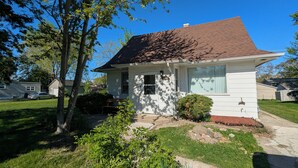 A single-story house with a brown roof, white siding, and a front porch.