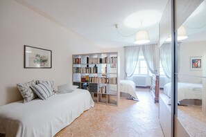 Une chambre avec une grande bibliothèque, un lit avec une literie blanche et un miroir.