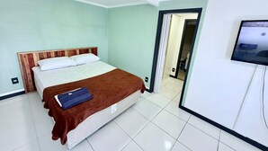 A hotel room with a bed, a television, and a bathroom visible through an open door. - Céu Beach club (Rio de Janeiro)
