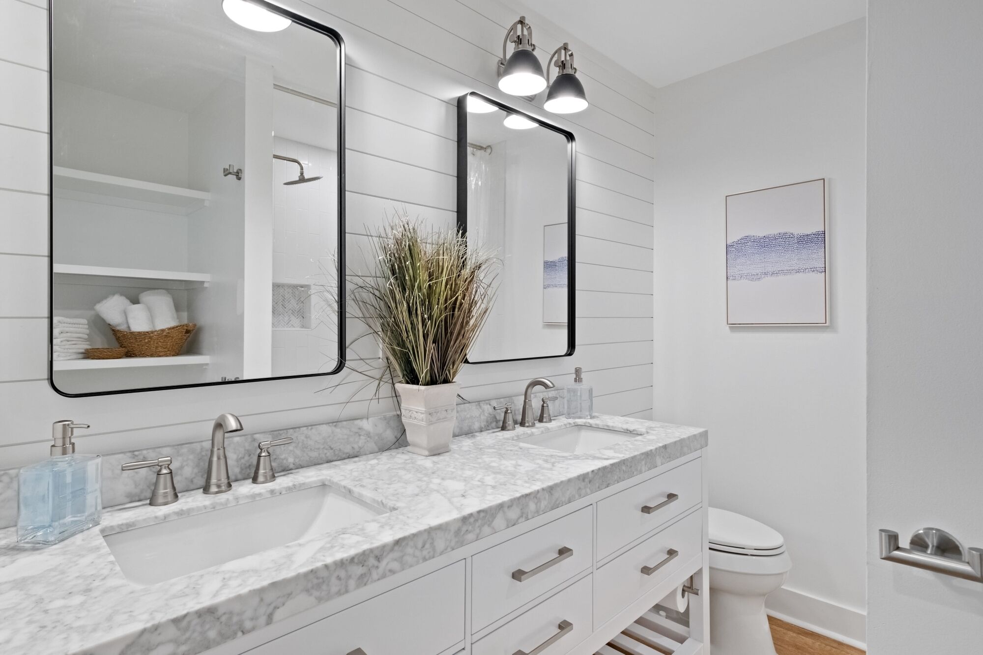 A bathroom with two sinks, a large mirror, and a potted plant.