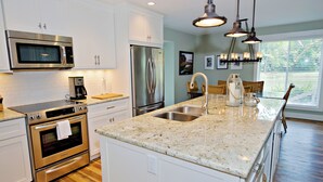 A modern kitchen with stainless steel appliances, a granite countertop, and a large island with a sink. - 1596 Lagoon Villas at The Sea Pines Resort (Hilton Head Island)