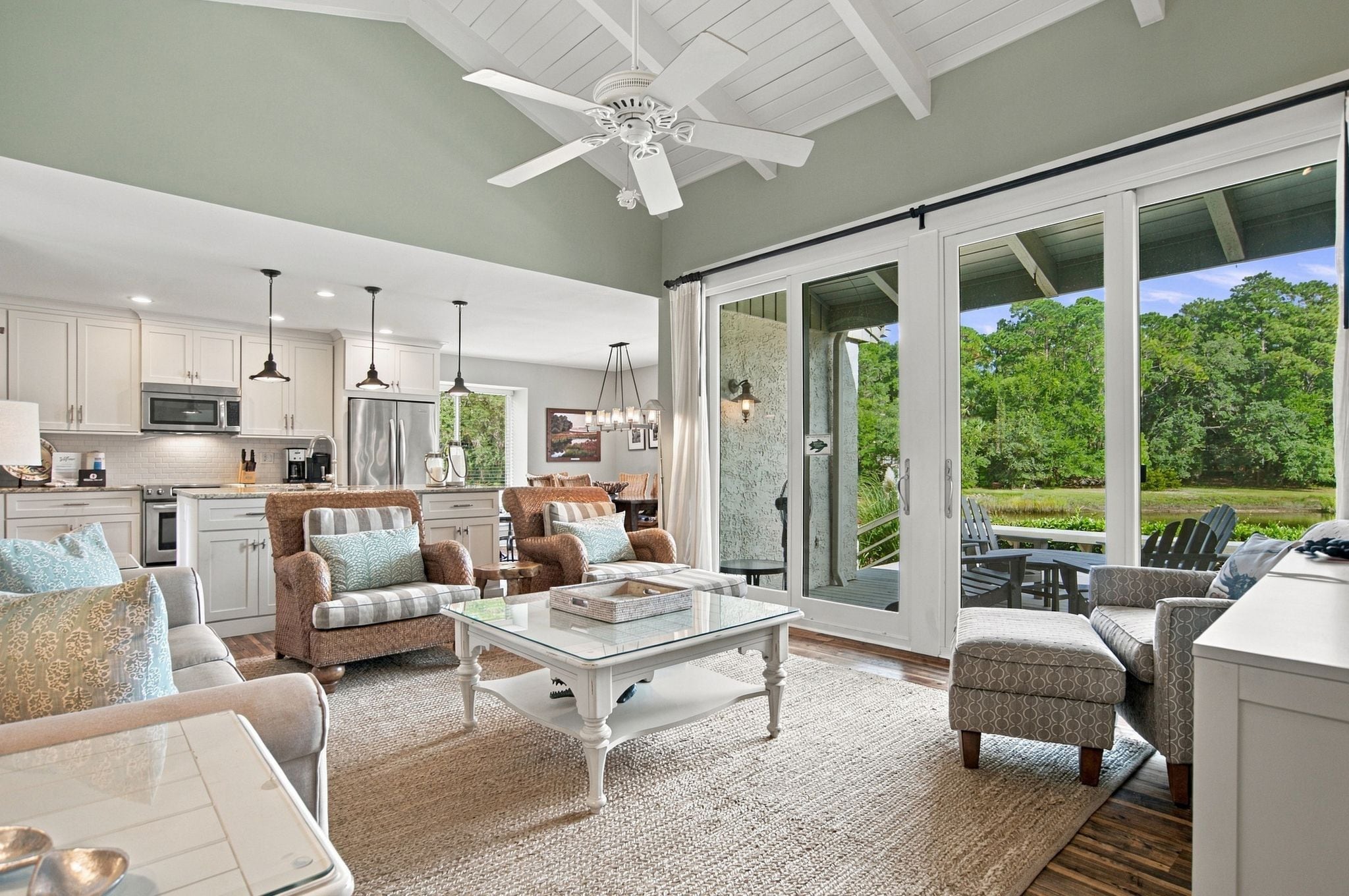A spacious living area with a large glass door leading to a patio, a kitchen with modern appliances, and a ceiling fan.